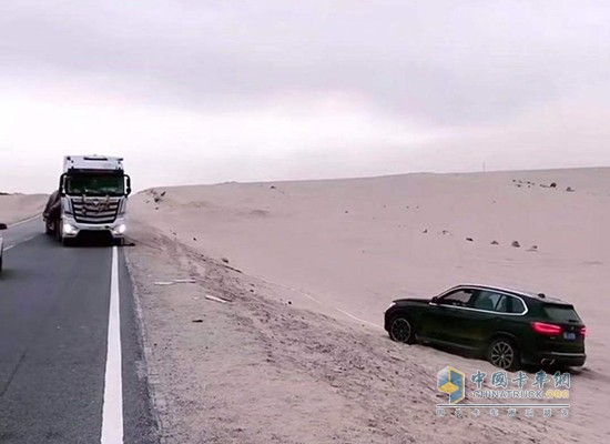 竇向永用卡車救陷入沙坑的轎車出來